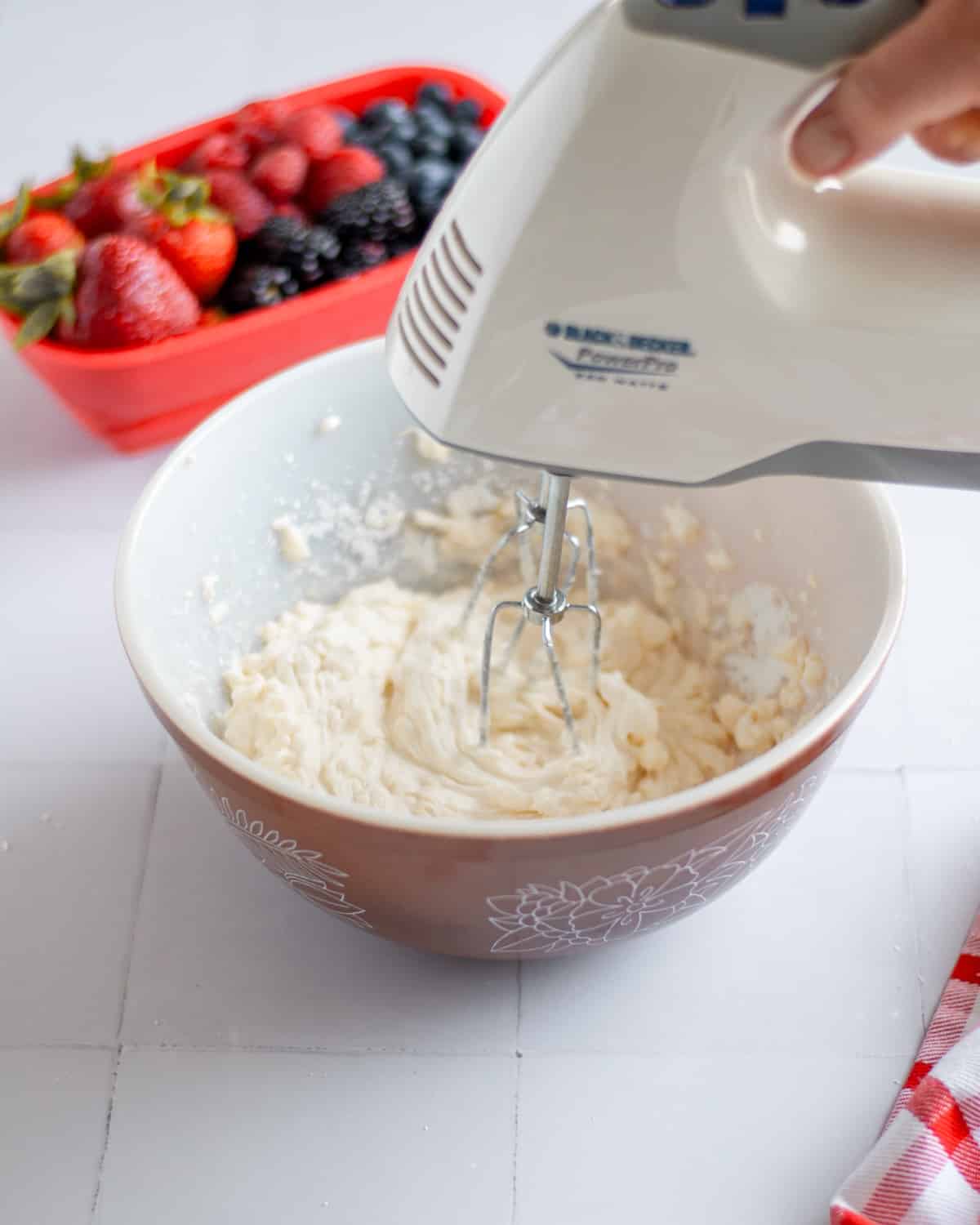 Process shot showing the fruit pizza frosting ingredients being mixed together with a handheld mixer.