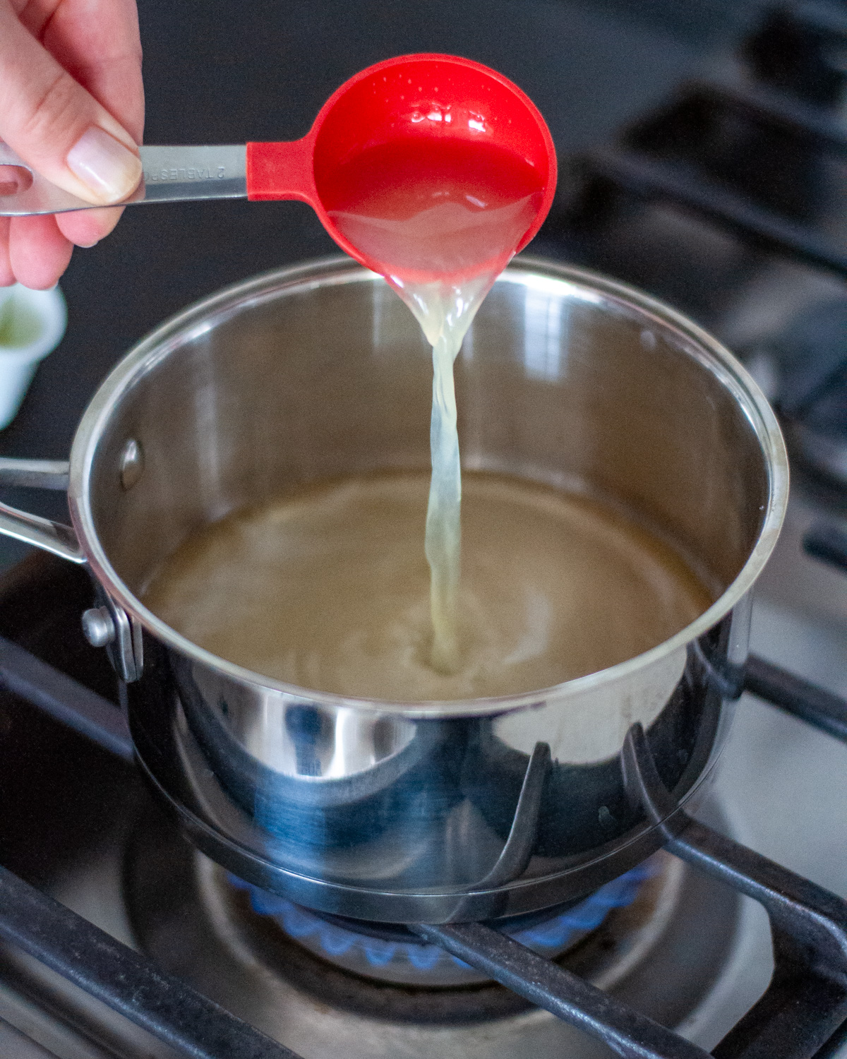 Process shot showing the fruit pizza glaze ingredients being added to a saucepan.