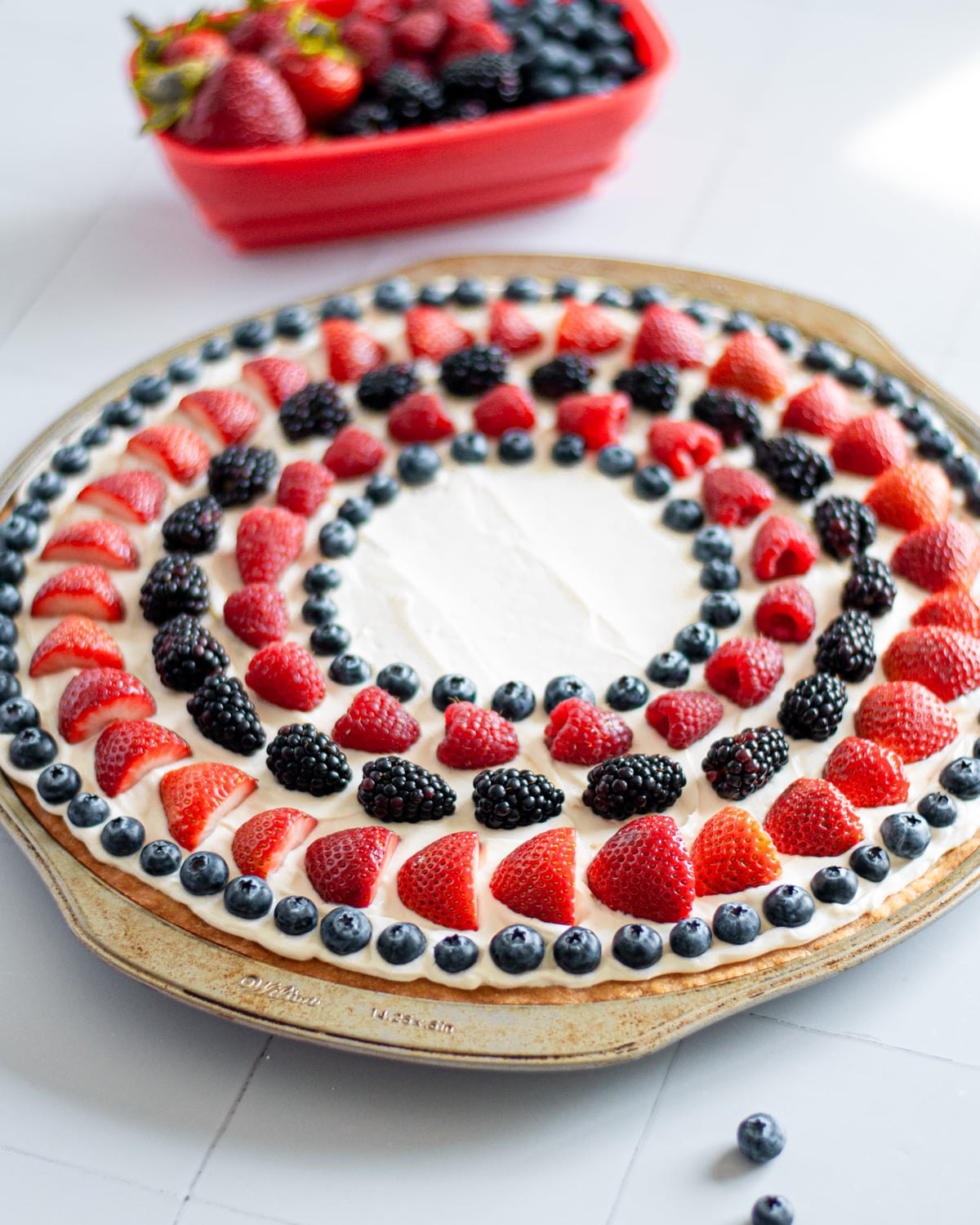 Process shot showing the fruit being arranged into circles on top of the frosting.