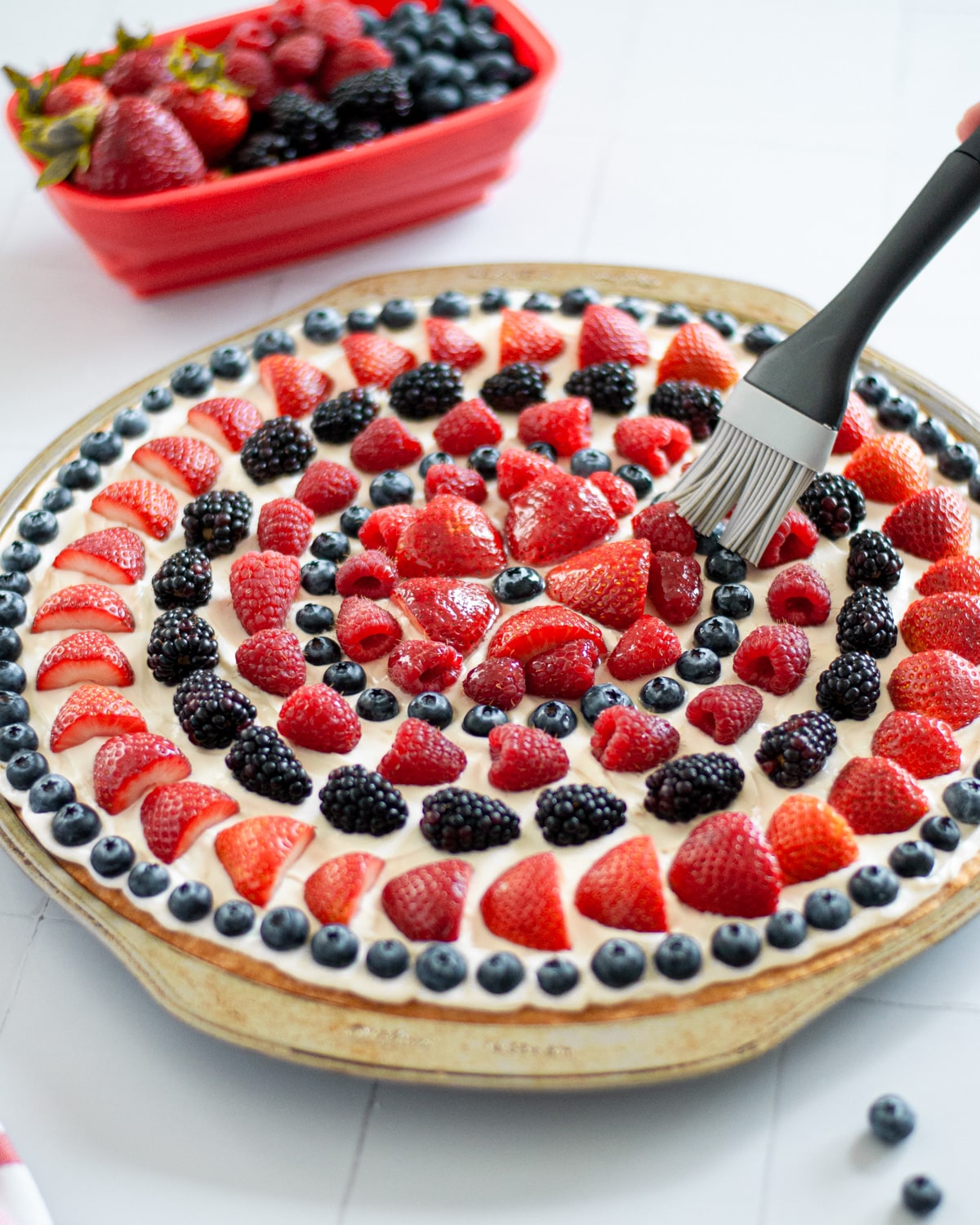 Process shot showing the fruit pizza glaze being brushed over the fruit design.
