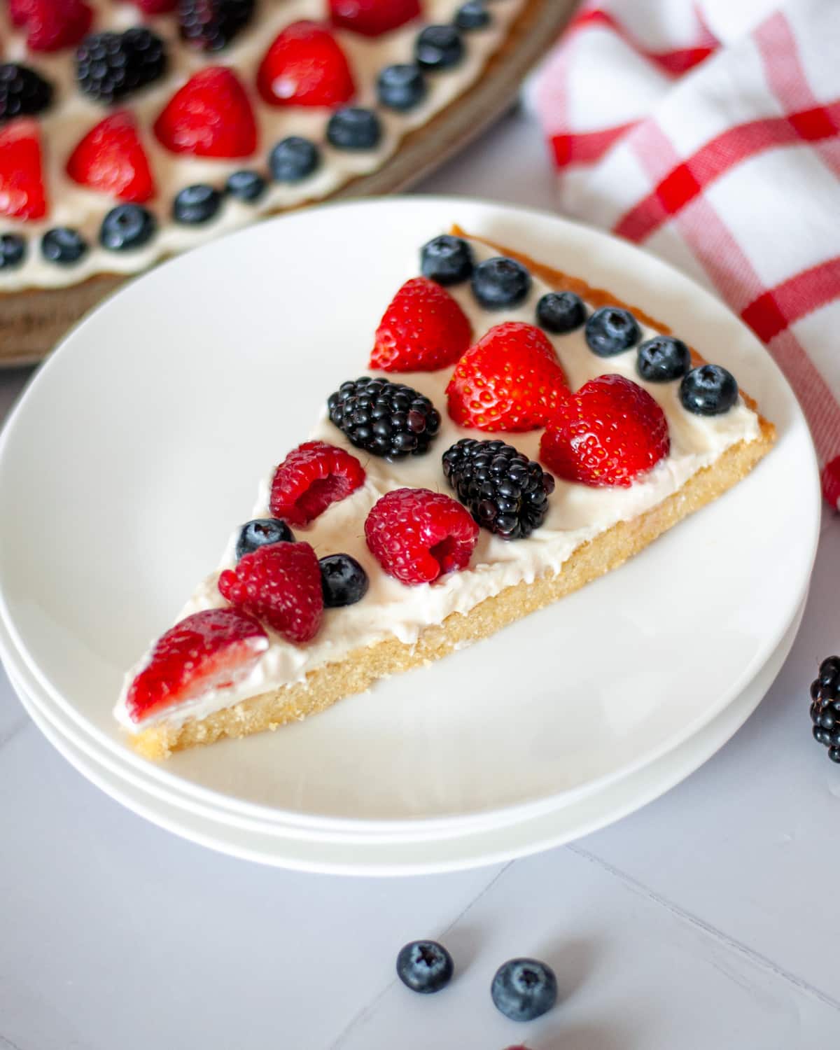 A slice of sugar cookie fruit pizza on a small serving plate.
