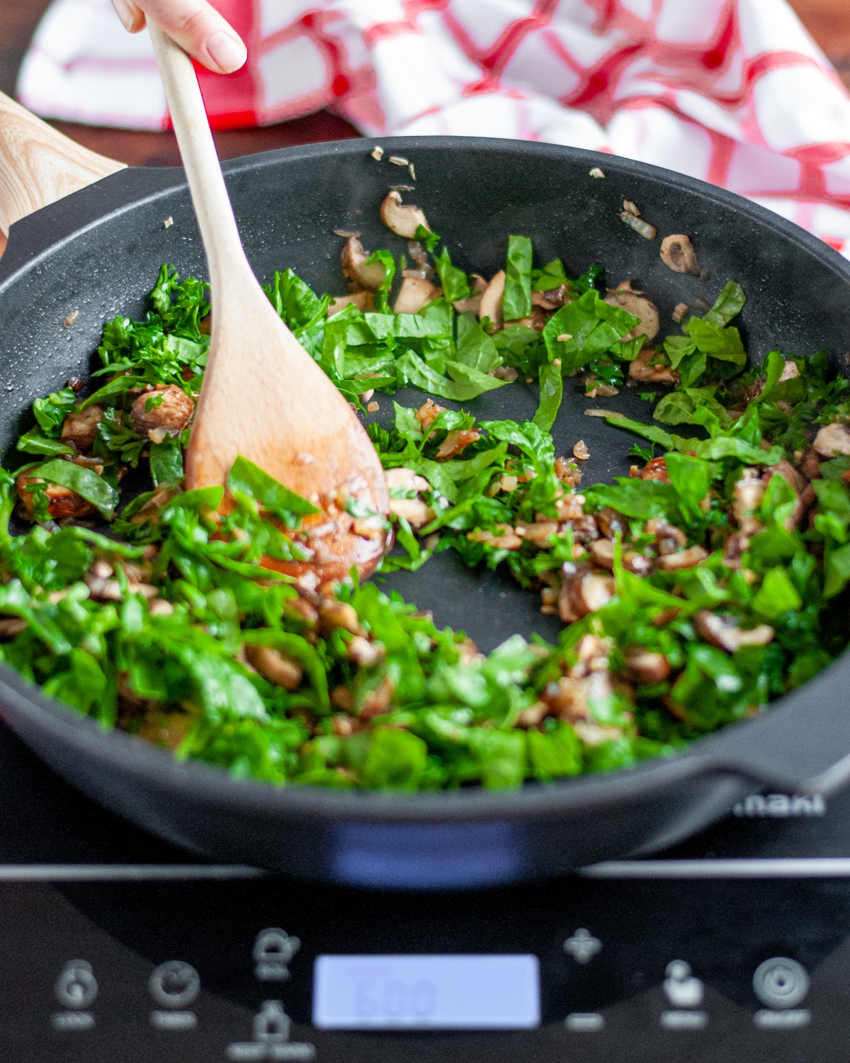 Process shot showing the parsley and spinach being cooked in the skillet.