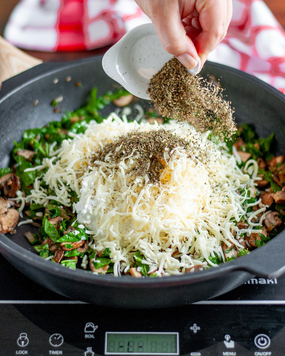 Process shot showing the Italian seasoning being added to the skillet.