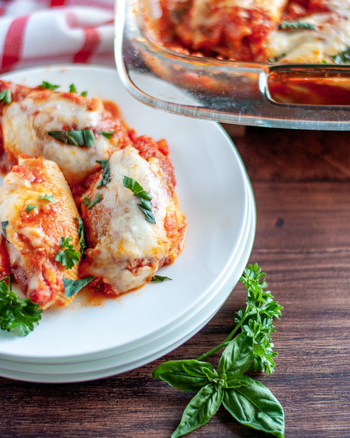 Three stuffed shells set onto a stack of white plates.