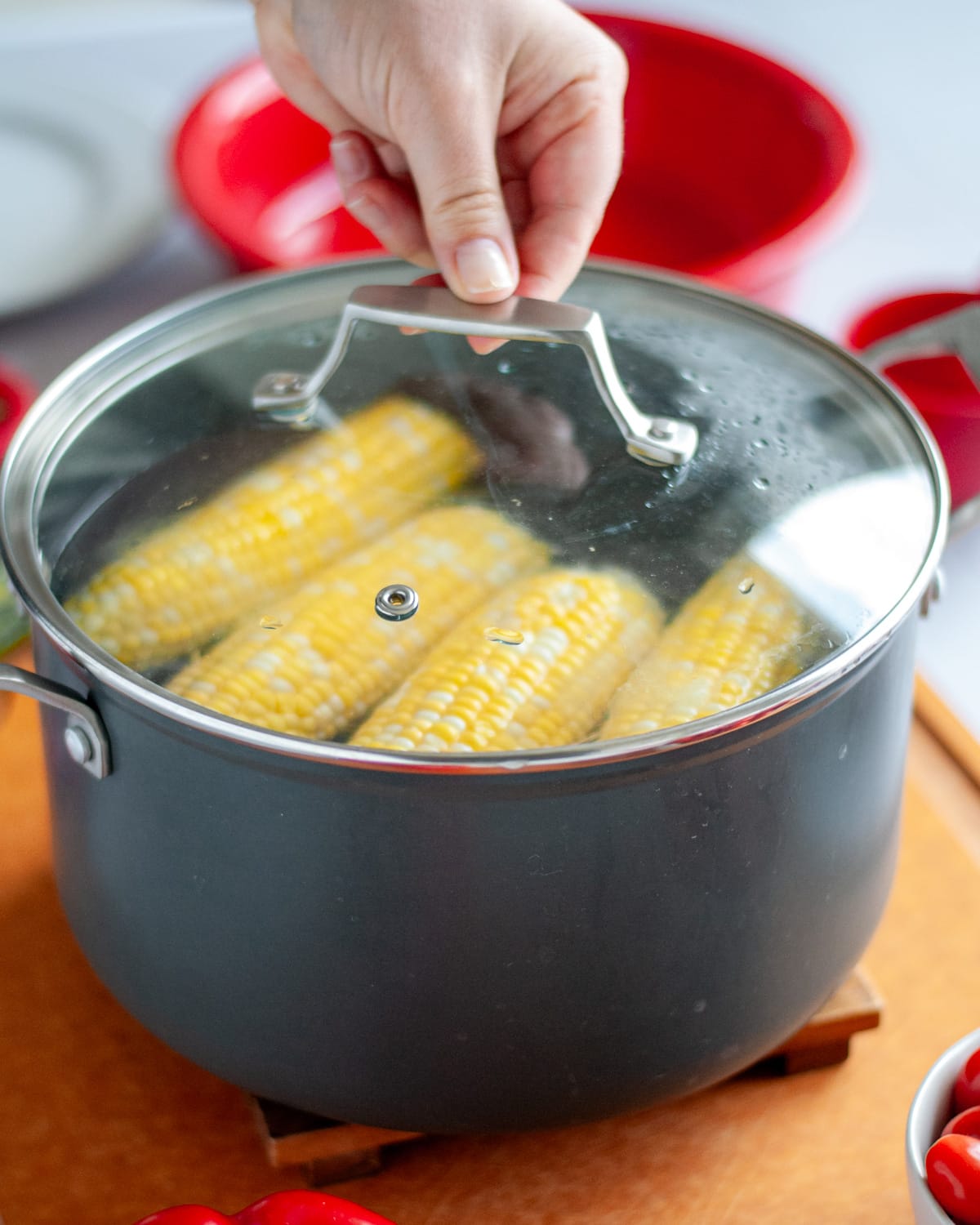 Process shot showing the lid being placed onto the corn in the hot water.