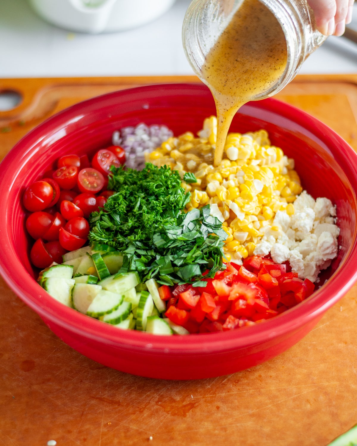 Process shot showing the dressing being poured over the salad ingredients.