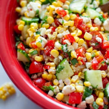 Close up of the summer corn salad in a large red bowl.