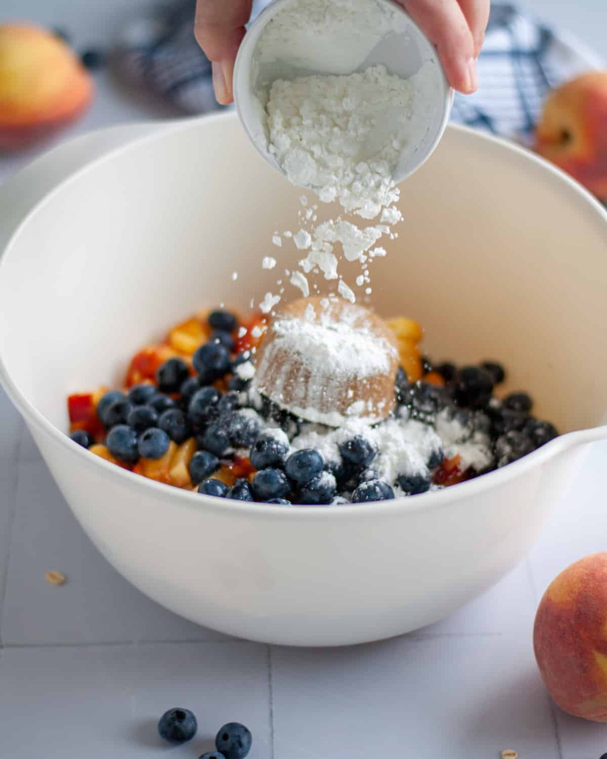 Process shot showing the cornstarch being poured over the other filling ingredients in a large mixing bowl.
