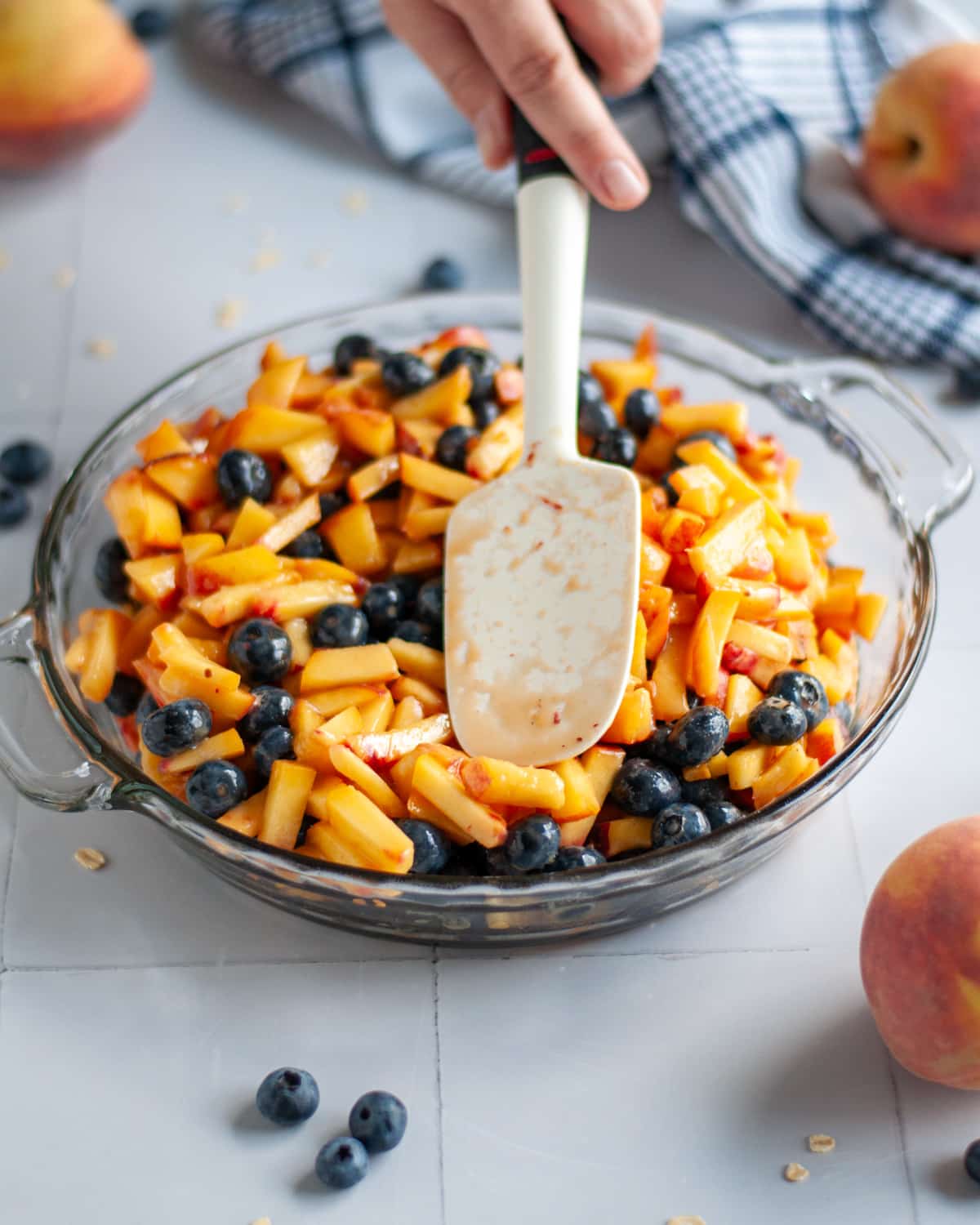 Process shot showing the fruit filling being spread into an even layer in the pie pan.