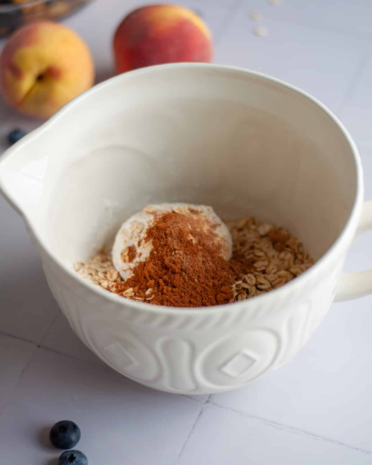 Process shot showing the oatmeal topping ingredients, excluding the butter, added to a mixing bowl.