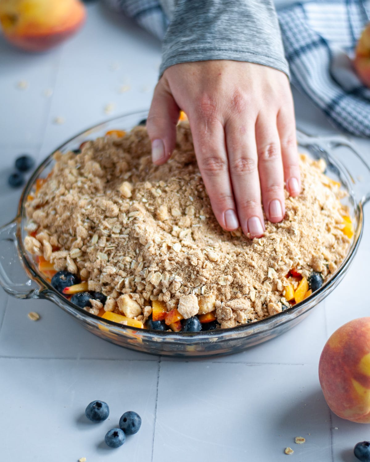 Process shot showing the oatmeal topping being spread into an even layer over the fruit filling.