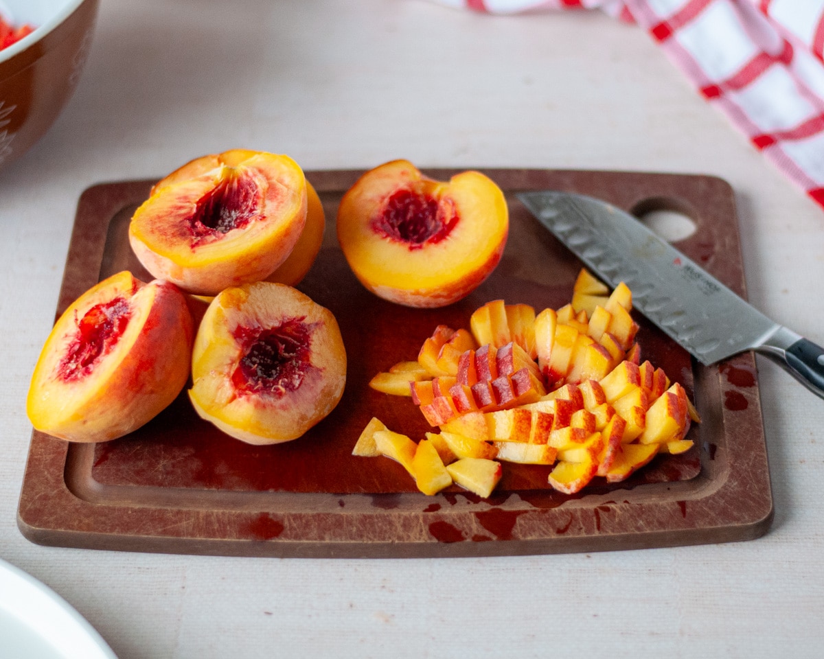 Process shot showing the fresh peaches being cut into bite-sized pieces.