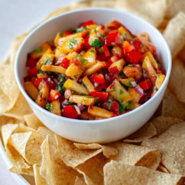 A bowl of peach salsa on a serving tray with tortilla chips.