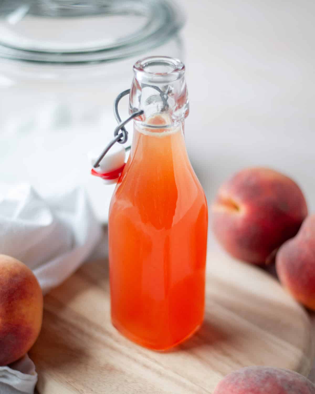 Close up of a glass bottle filled with peach syrup.