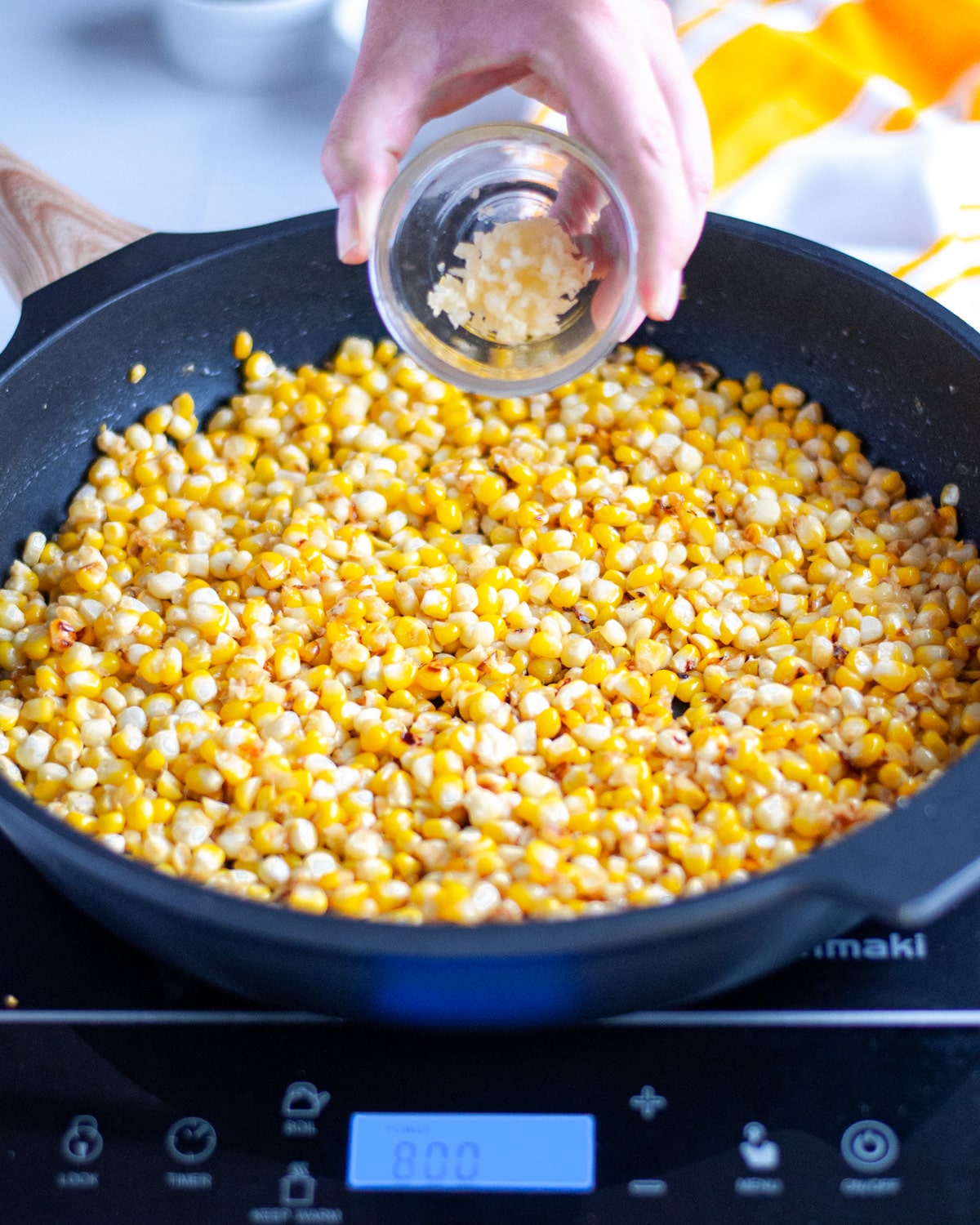 Process shot showing the minced garlic being added to the corn.