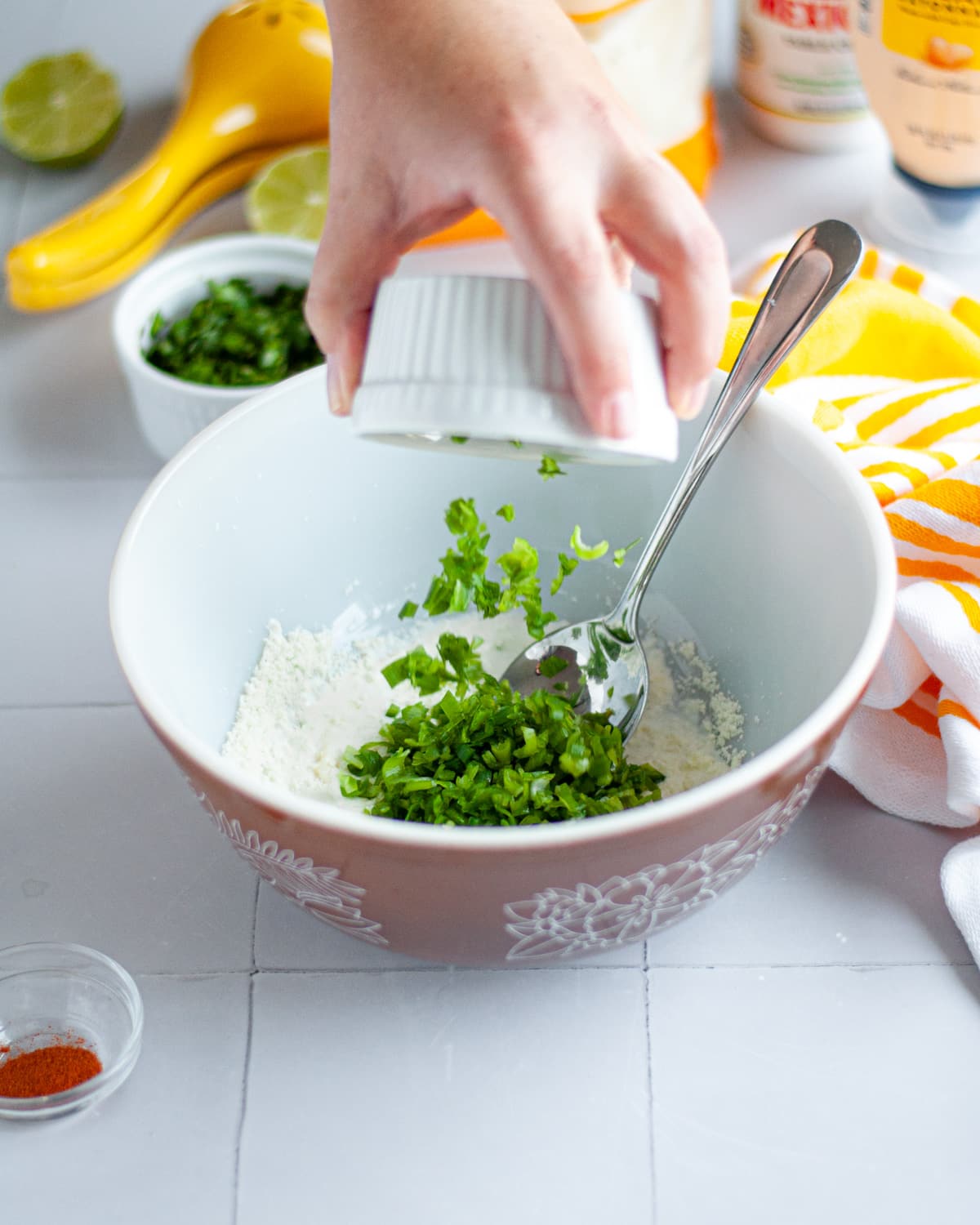 Process shot showing the elote corn salad dressing ingredients being added to a mixing bowl.