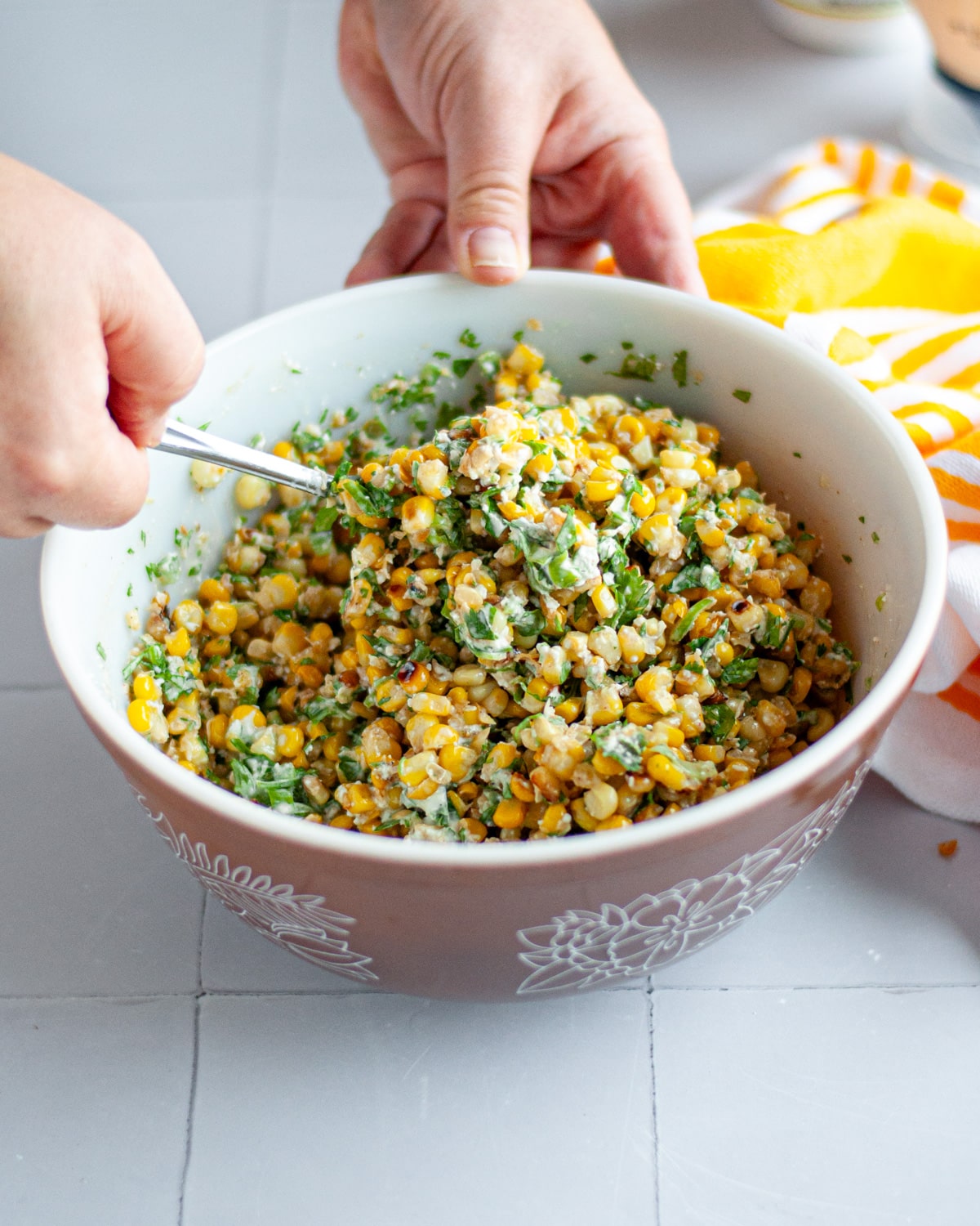 Process shot showing the elote corn salad being stirred together.