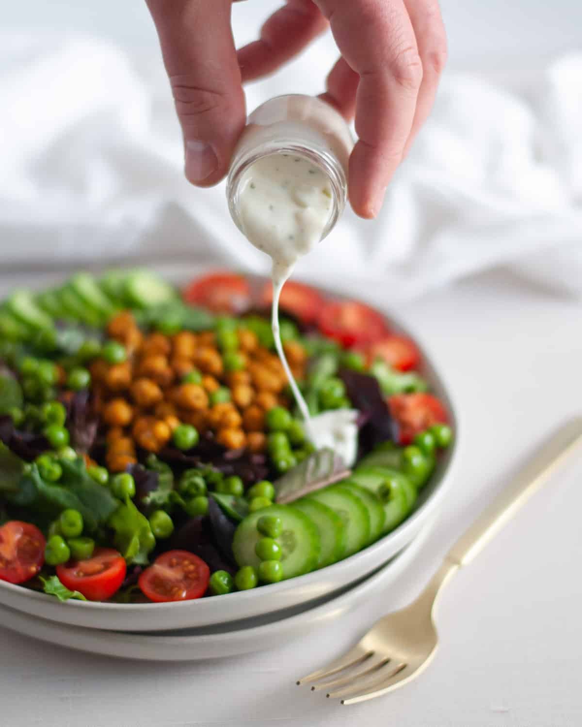 Dressing being poured onto Close up of a plate filled with a Curry Roasted Chickpea Salad.