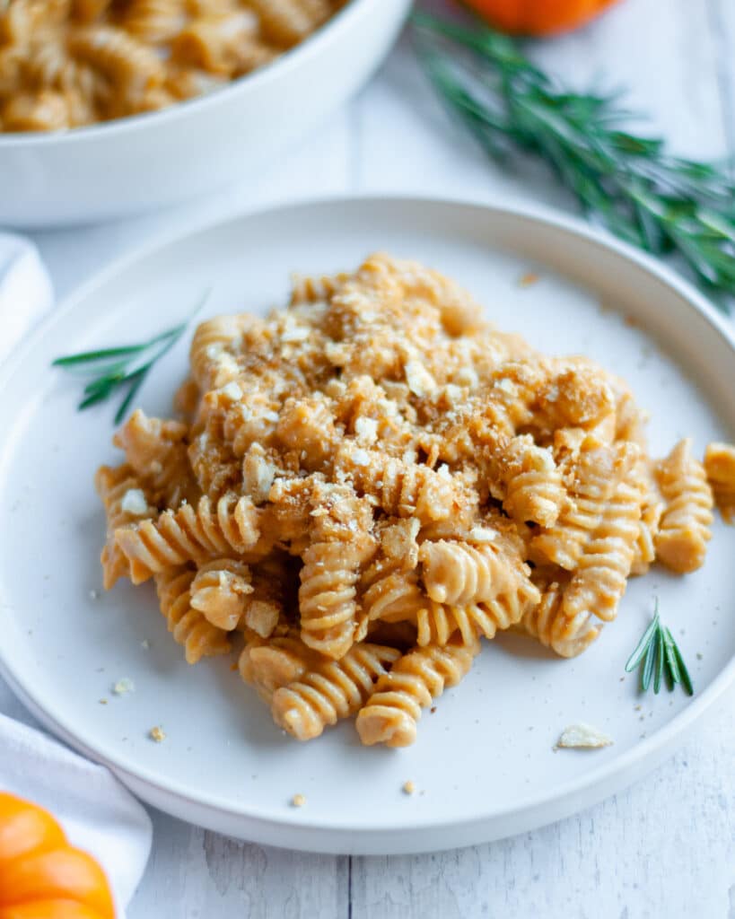 Close up of a plate of pumpkin mac n cheese topped with toasted cracker crumbs.
