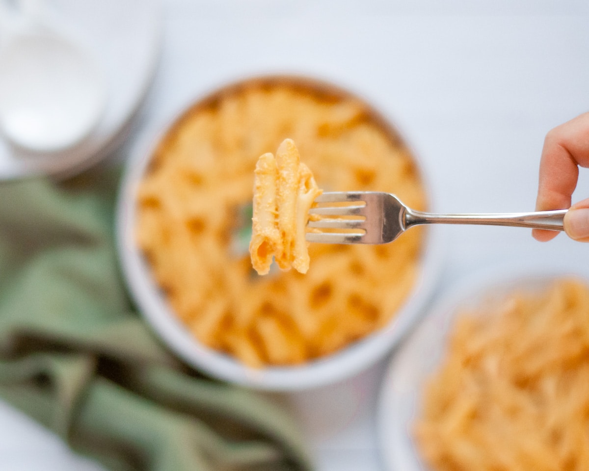 Top down shot of a Creamy Pumpkin Pasta with Boursin Cheese with a forkful of the pasta held up to the camera.