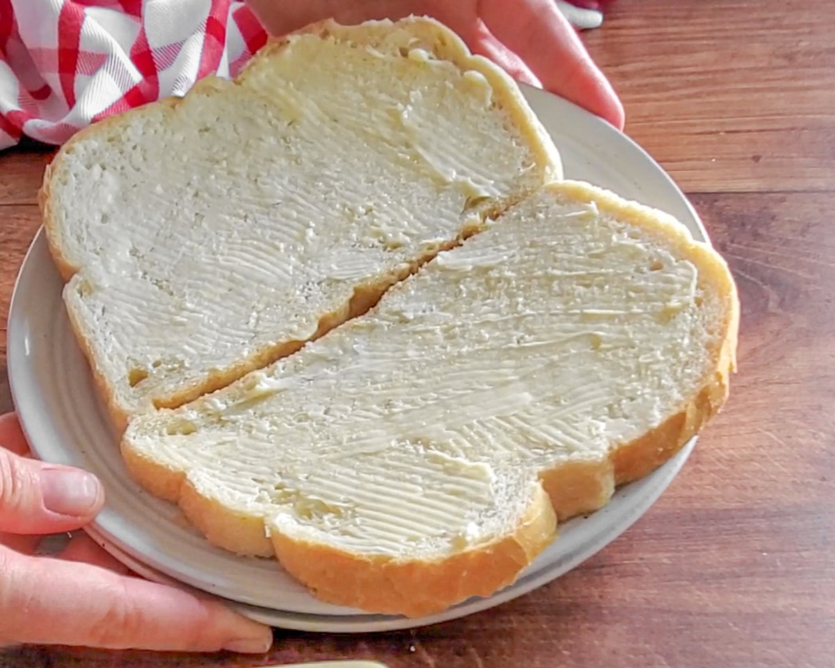 Process shot showing the bread slices buttered.