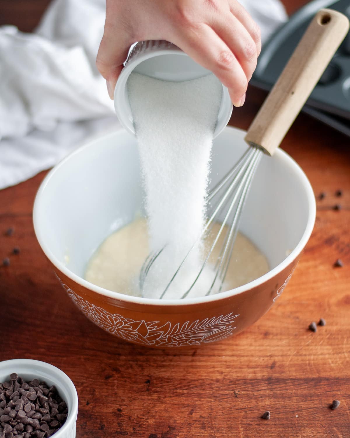 Process shot showing the granulated sugar being added to the wet ingredients.
