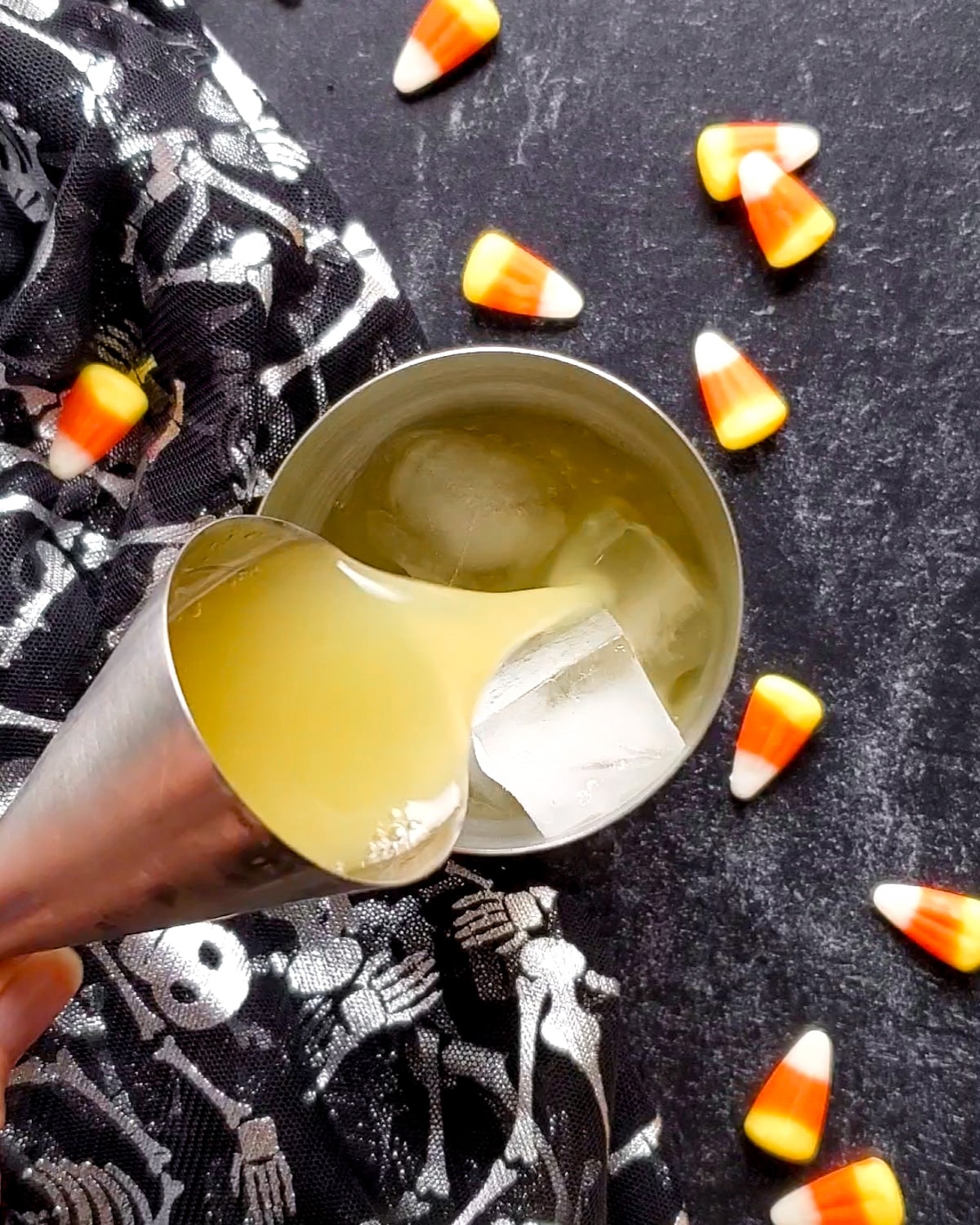 Process shot showing the pineapple juice being poured over the vodka and ice in the cocktail shaker.