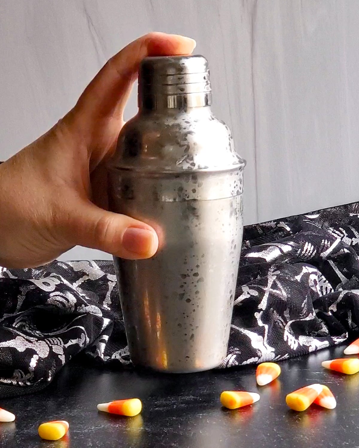 Process shot showing the the cocktail shaker capped and being shaken to chill.