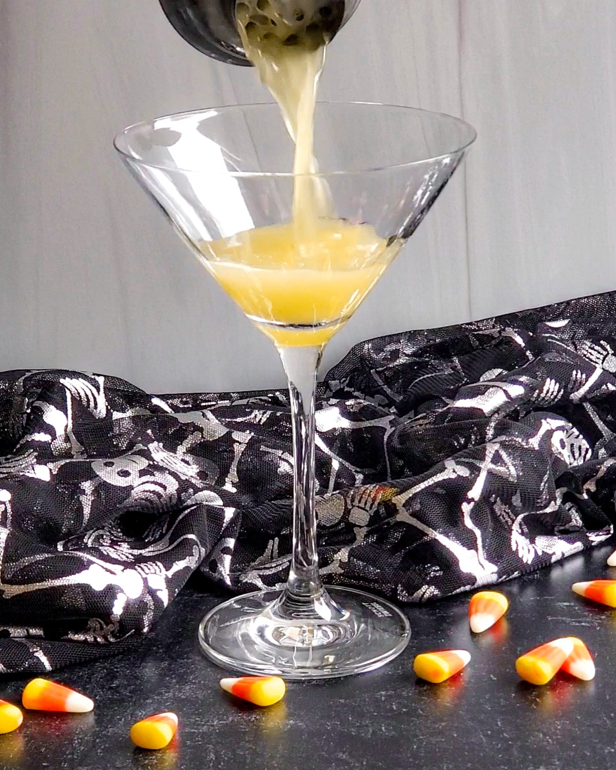 Process shot showing the pineapple juice and vodka being poured over into the martini glass.