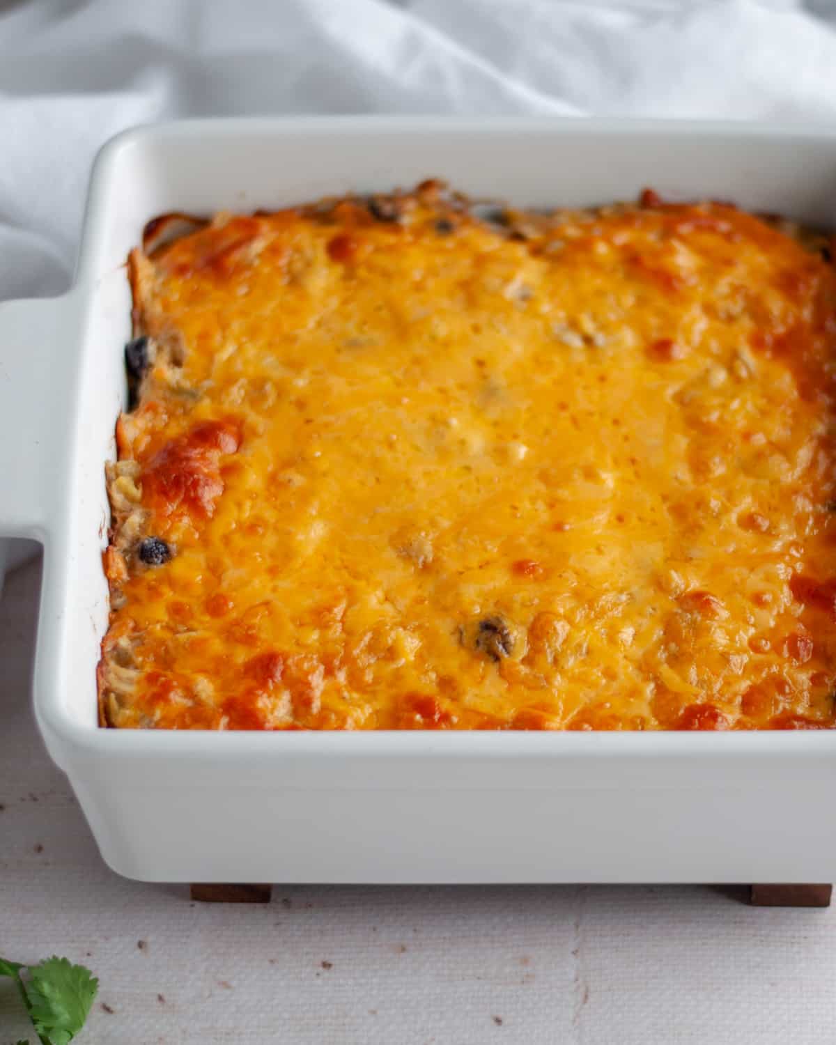 Process shot showing the enchilada casserole fresh from the oven with a bubbling and melted cheese topping.