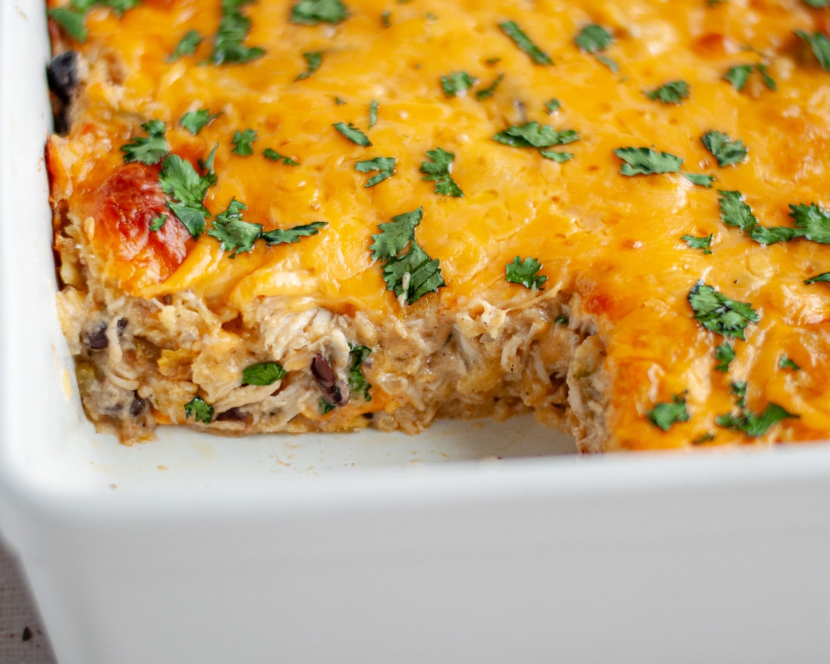 Close up of the baked chicken enchilada casserole topped with fresh cilantro, showing the interior after a slice has been removed.