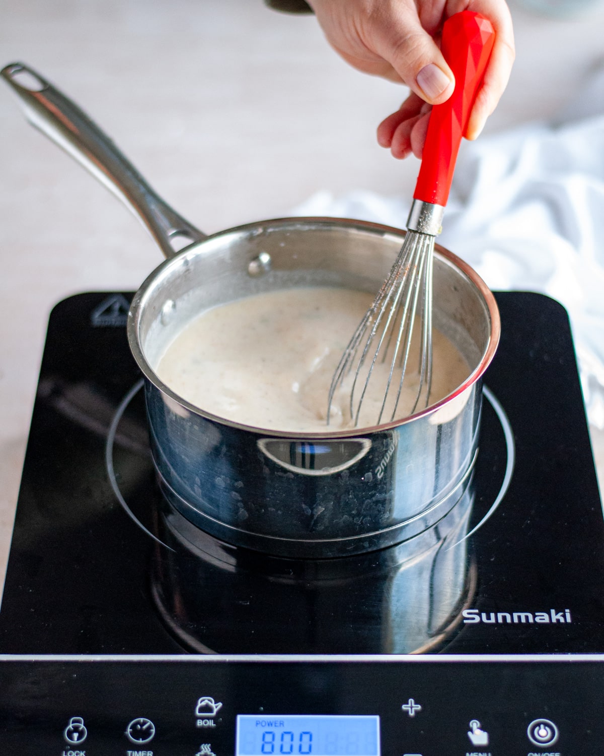Process shot of the cream of celery soup being whisked together as it cooks on the stovetop.
