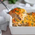 Close up of a slice of chicken enchilada casserole being scooped out of the casserole dish, ready to serve!