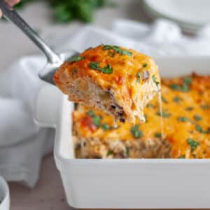 Close up of a slice of chicken enchilada casserole being scooped out of the casserole dish, ready to serve!