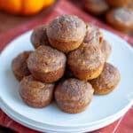 A plate stacked high with pumpkin mini muffins.