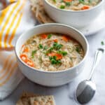 A bowl of lemon chicken and rice soup garnished with fresh parsley.