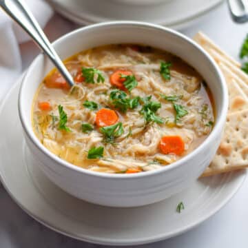 Feature image showing a bowl of lemon chicken and rice soup with a spoon in it and garnished with fresh parsley.