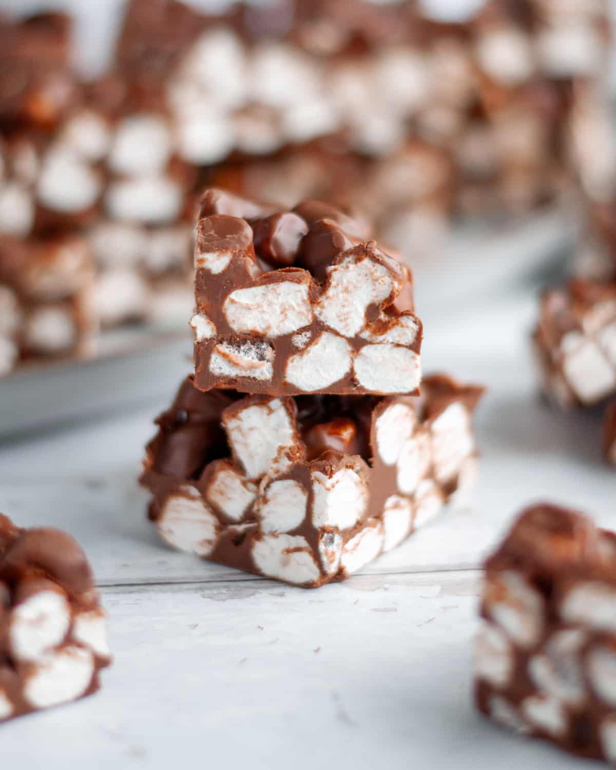 Close up of a stack of two rocky road bars, surrounded by other squares of no bake rocky road.