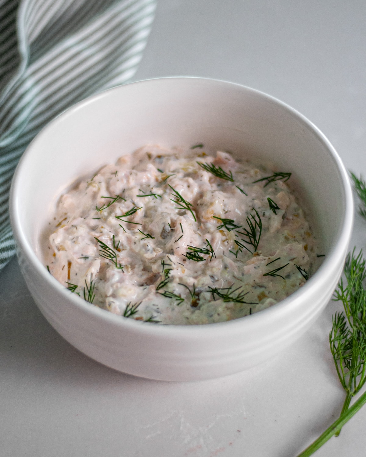 Process shot showing the tuna salad with pickles in a bowl after the ingredients were mixed together and topped with extra fresh dill.
