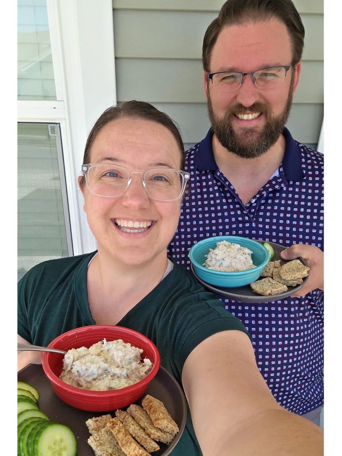 Selfie of Meredith and her husband holding their lunches with include a bowl of dill pickle tuna salad using greek yogurt, toast pieces, and cucumber slices.