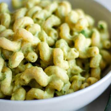 Close up of a white bowl of creamy zucchini pasta.