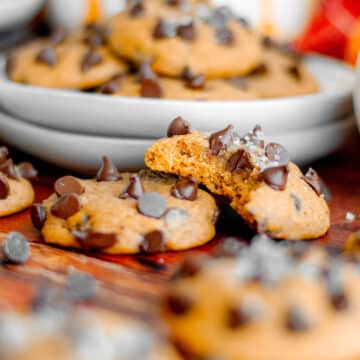 Feature image for our pumpkin and chocolate chip cookies recipe, showing a close up of a pumpkin cookie with a bite out of it leaning on another cookie.