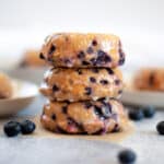 Straight on shot of three lemon blueberry baked donuts stacked on one another, with blueberries and additional donuts around it.