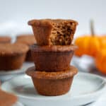 Stack of three pumpkin protein muffins with a bite taken out of the top muffin.